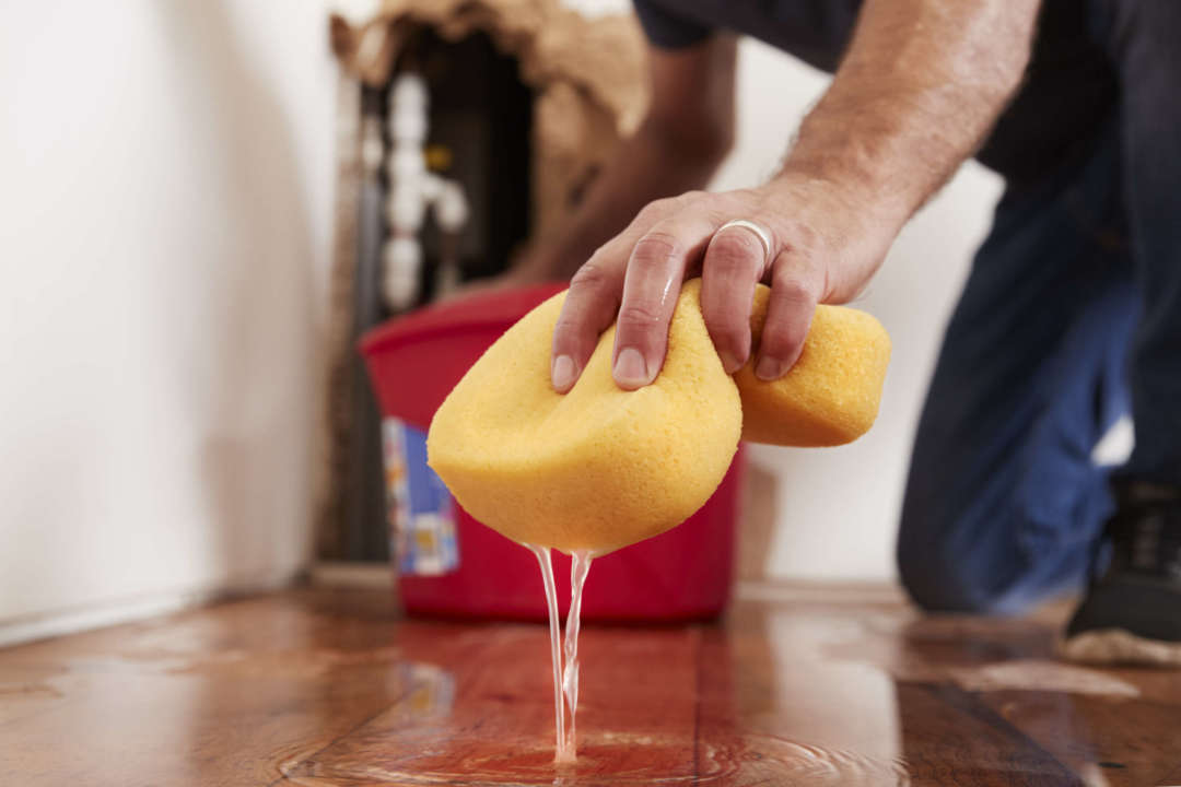 Man mopping up water from the floor with a sponge, detail