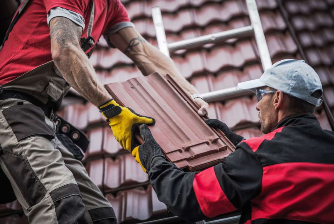 Roofers hand tiles to each other