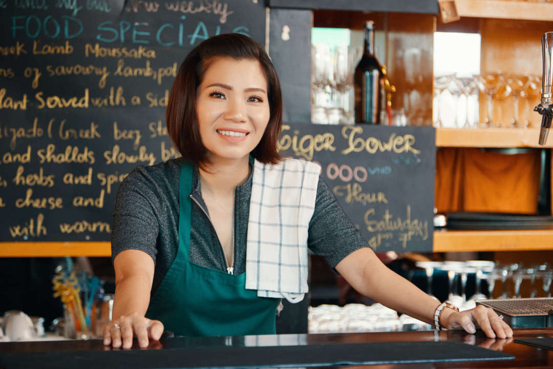 Coffee Shop Owner standing with a smile because she's covered by Fero Insurance.