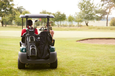 Rear View Of Couple Playing Golf Driving Buggy Along Fairway On Red Letter Day Rear View Of Couple Playing Golf Driving Buggy Along Fairway On Red Letter Day